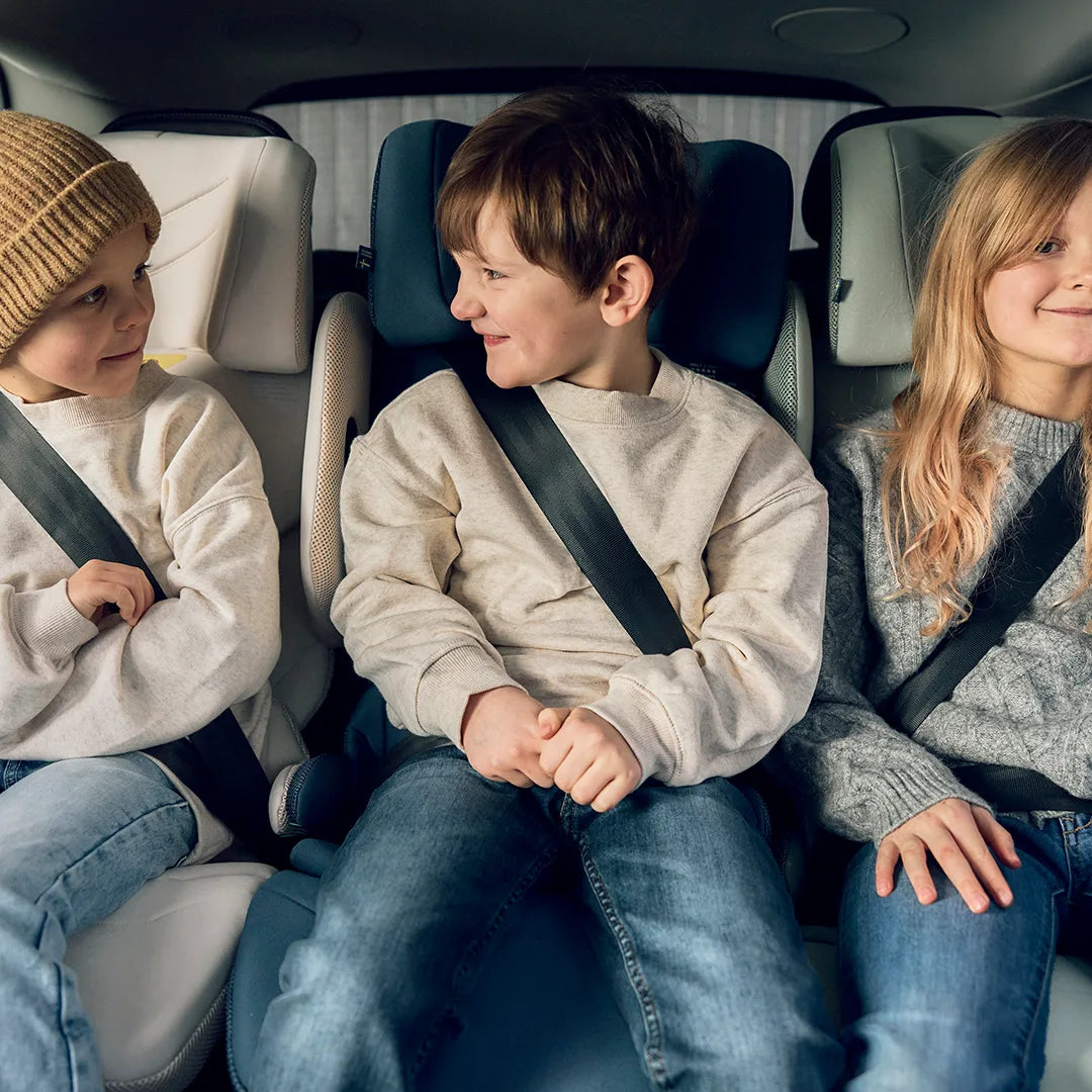 Tre bältesstolar med ryggstöd av modellen Axkid Up i rad i bilens baksäten.