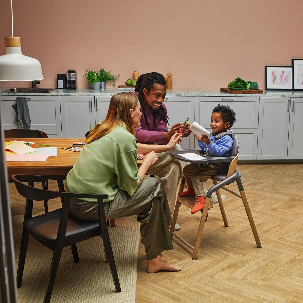 Barn sitter i Bugaboo Giraffe-stol med bricka – hemma vid köksbordet.