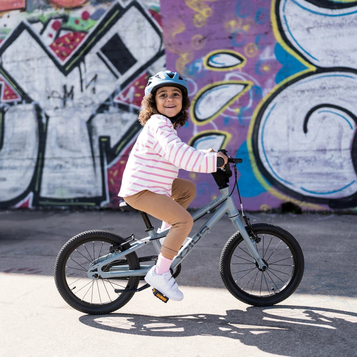 Barn som cyklar på Puky LS-PRO 16 i askblå med hjälm