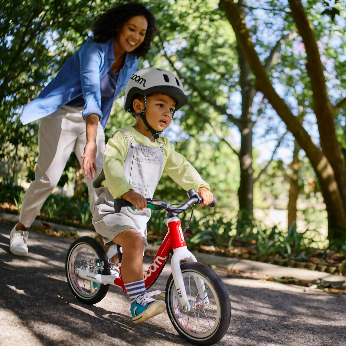 Barn med cykelhjälm springer på Woom Go 1 balanscykel 12 tum